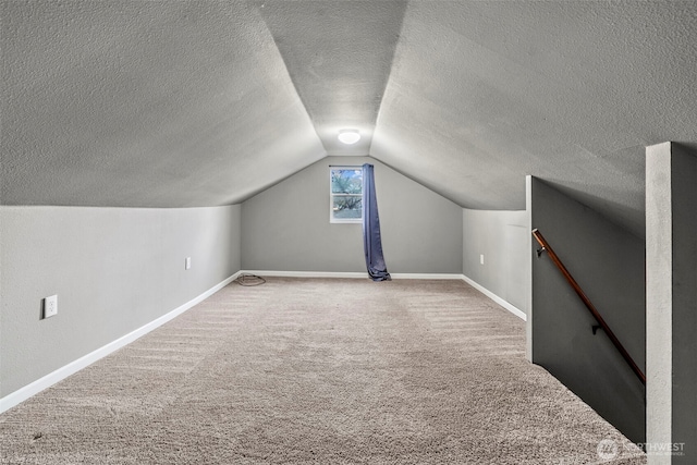 additional living space featuring lofted ceiling, baseboards, carpet floors, and a textured ceiling