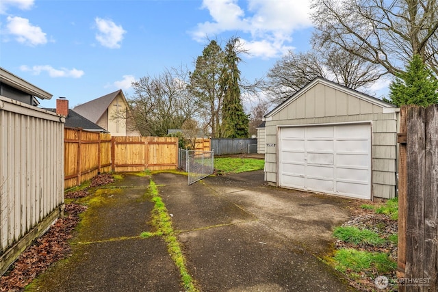 detached garage featuring a gate, fence, and driveway