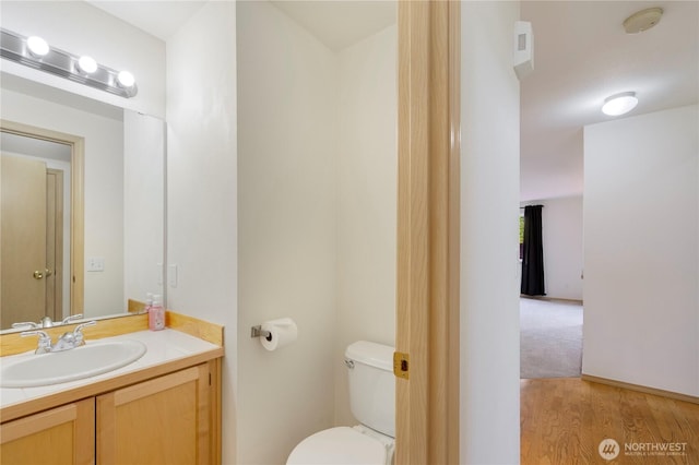 bathroom featuring toilet, wood finished floors, and vanity