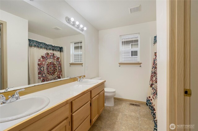 full bath with toilet, visible vents, and a sink