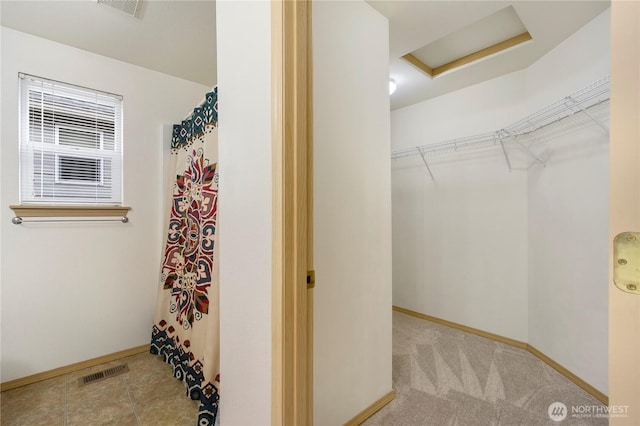 spacious closet with visible vents, attic access, and carpet