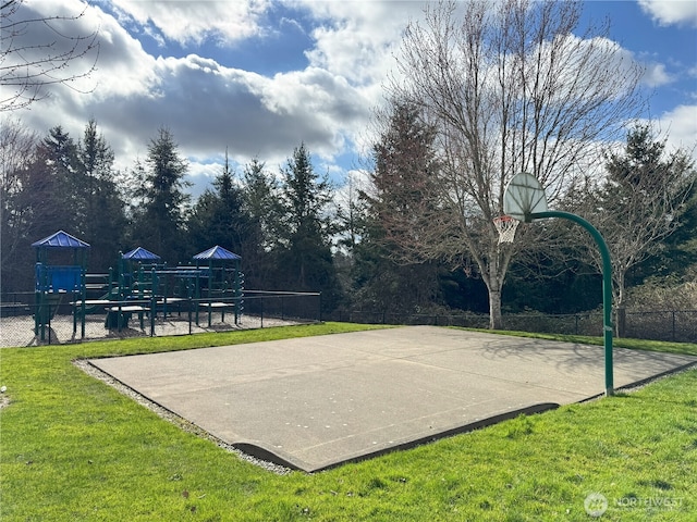 view of basketball court featuring playground community, community basketball court, a lawn, and fence