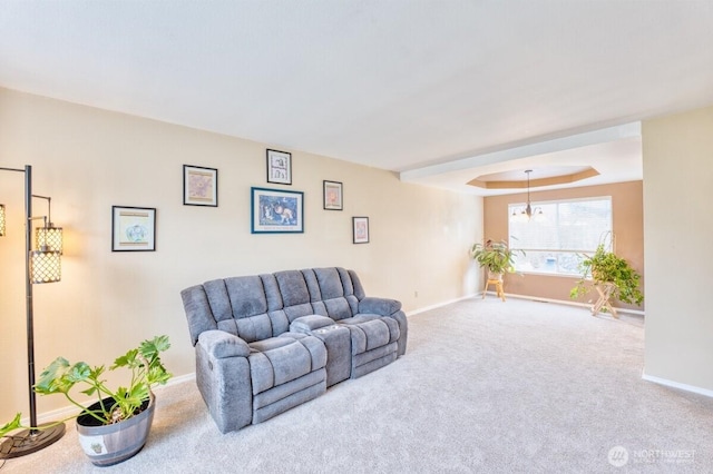 living room featuring a chandelier, baseboards, a tray ceiling, and carpet