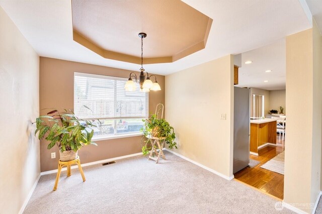 living area featuring a tray ceiling, visible vents, baseboards, and carpet floors