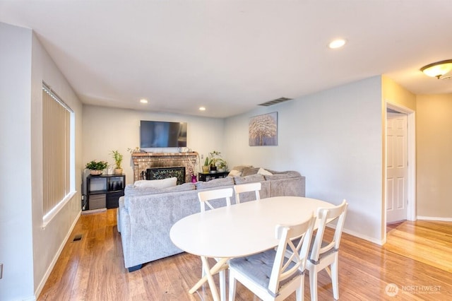 dining area with visible vents, light wood finished floors, baseboards, recessed lighting, and a fireplace