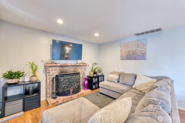 living area featuring visible vents, recessed lighting, a fireplace, and wood finished floors