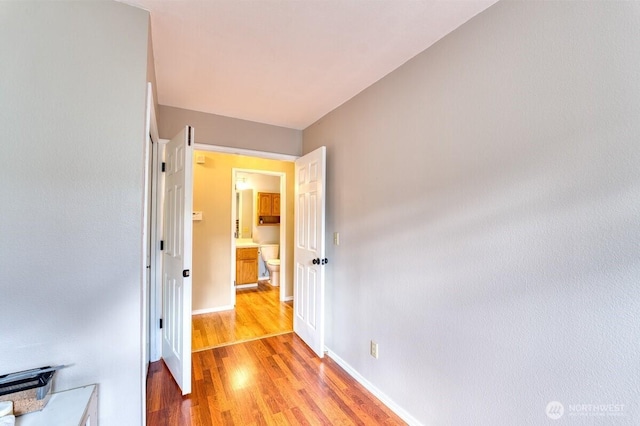 hall featuring light wood-style flooring and baseboards