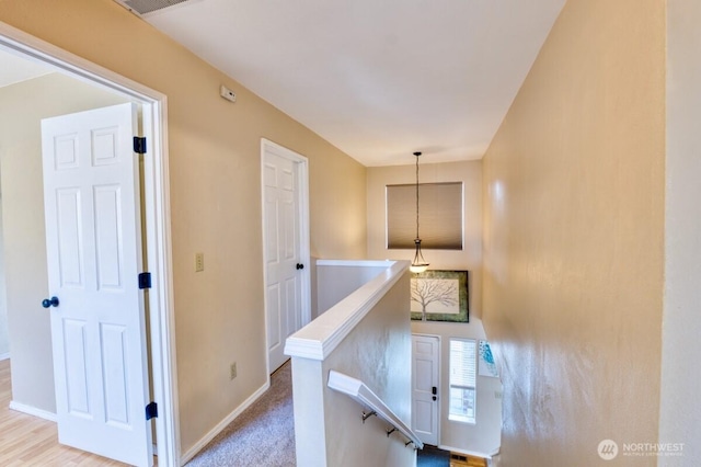 hall with baseboards, an upstairs landing, and carpet