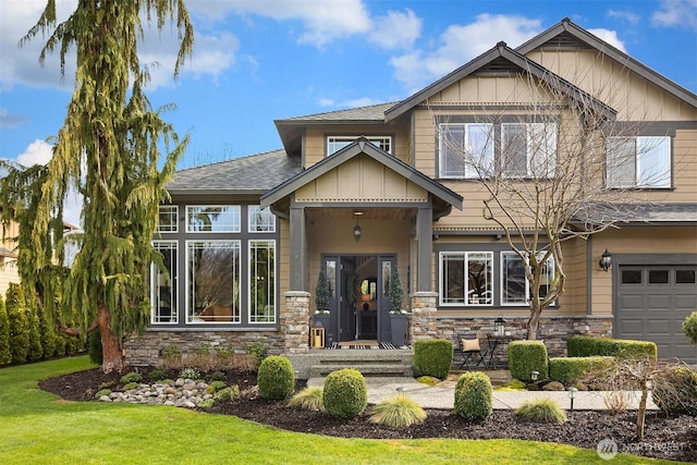 view of front of property featuring stone siding, a garage, board and batten siding, and a front yard