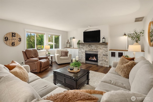 living area with a fireplace, wood finished floors, and visible vents