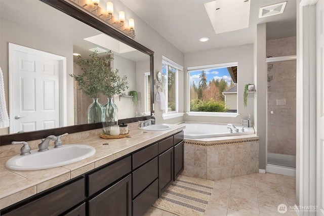 full bathroom with a sink, a stall shower, a skylight, and a bath