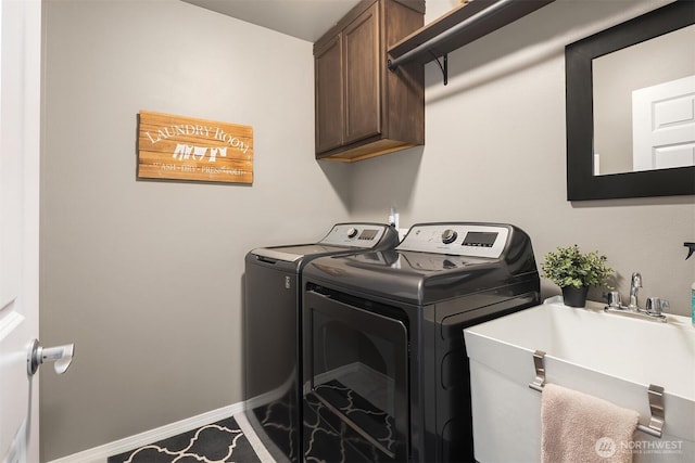 laundry area with baseboards, cabinet space, independent washer and dryer, and a sink