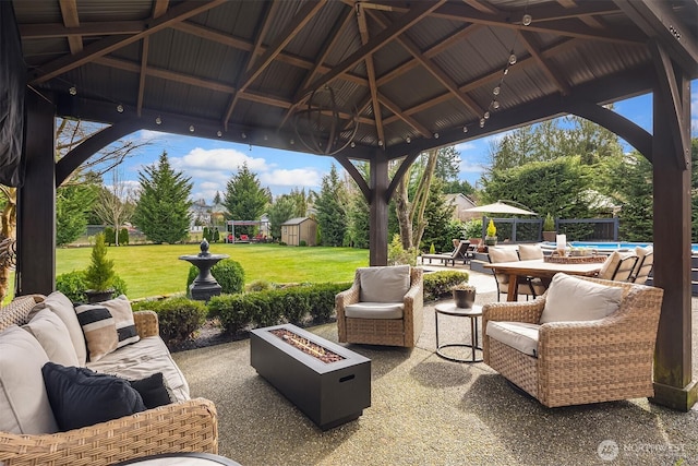 view of patio with an outbuilding, a gazebo, a storage shed, an outdoor living space with a fire pit, and an outdoor pool