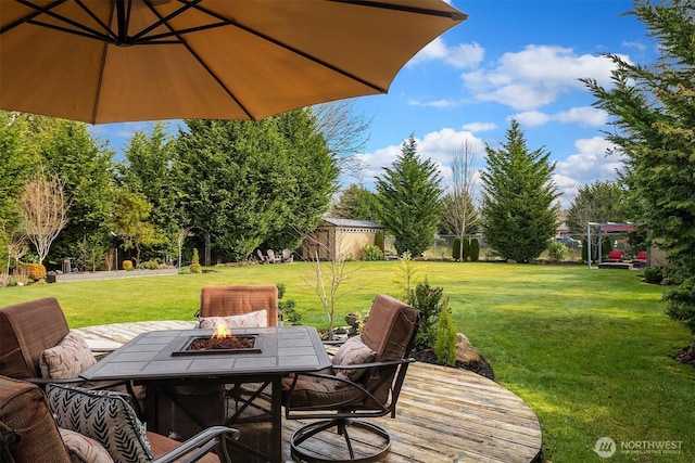 deck featuring an outbuilding, an outdoor fire pit, a storage shed, and a yard