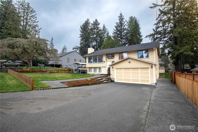 view of front of property featuring fence, a chimney, a front lawn, a garage, and aphalt driveway