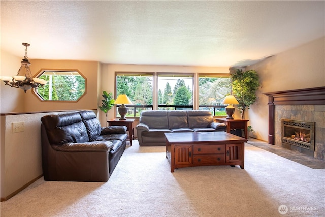 living area with a tiled fireplace, a notable chandelier, carpet, and a textured ceiling