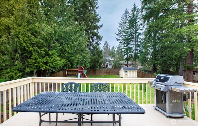 wooden deck with a storage unit, an outbuilding, a fenced backyard, a playground, and a yard