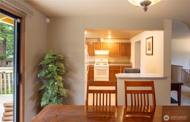 kitchen featuring under cabinet range hood, white gas range oven, and light countertops