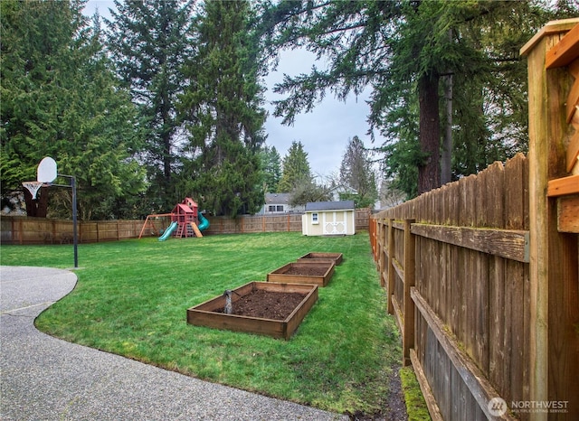 view of yard featuring a fenced backyard, a storage shed, an outdoor structure, and a playground