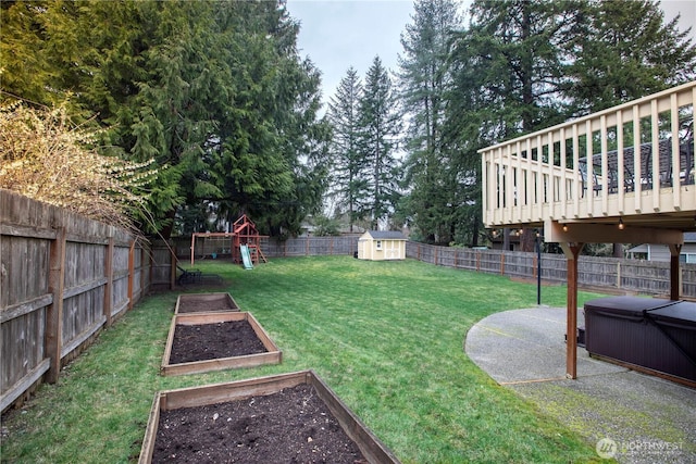 view of yard with a hot tub, a playground, a fenced backyard, an outdoor structure, and a vegetable garden