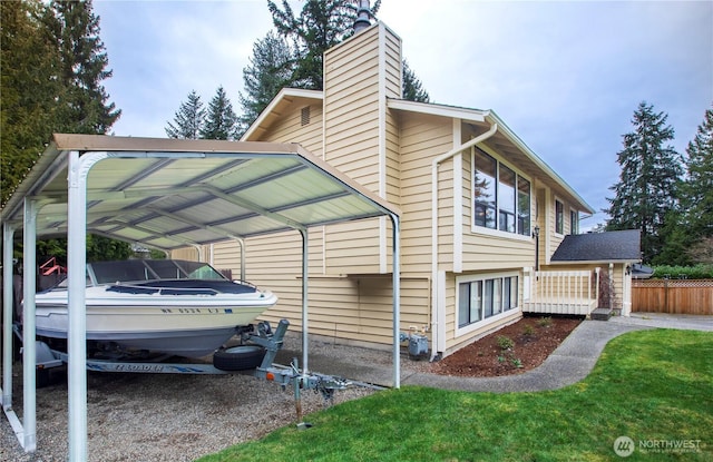 view of side of home featuring a carport, fence, and a chimney