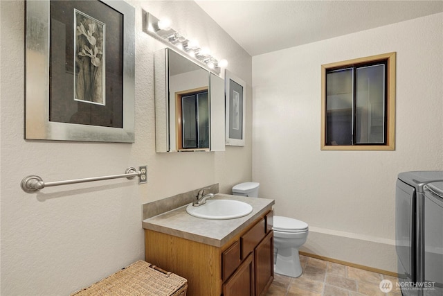 bathroom with washer and dryer, toilet, and vanity