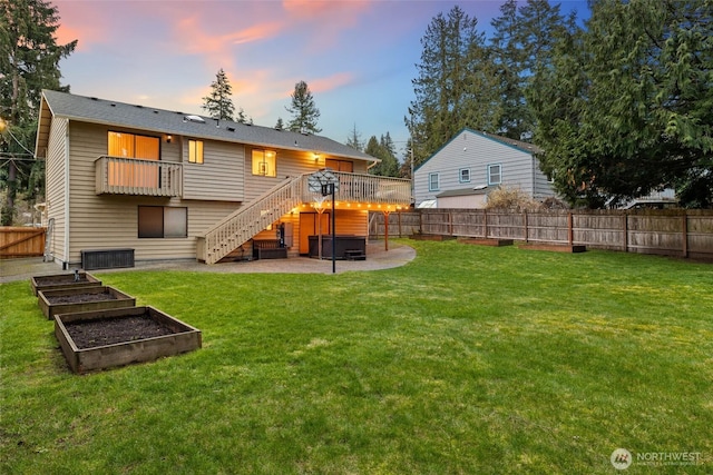 back of property at dusk with a patio, stairway, a garden, a yard, and a fenced backyard