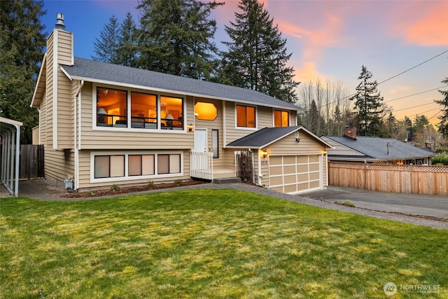 raised ranch featuring fence, aphalt driveway, a front yard, a chimney, and a garage