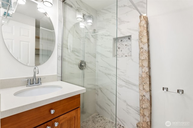 bathroom with a marble finish shower and vanity