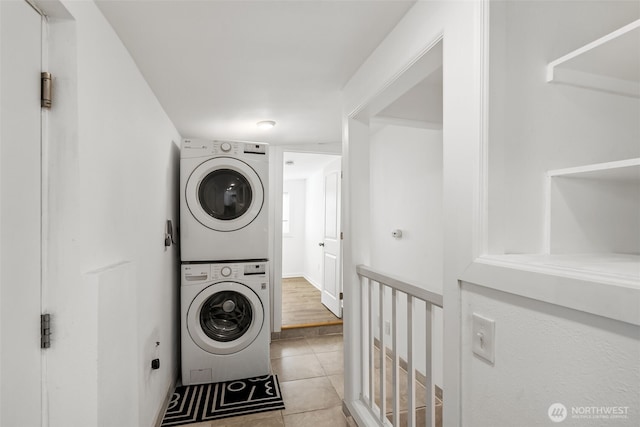 washroom with light tile patterned floors, stacked washer / drying machine, and laundry area