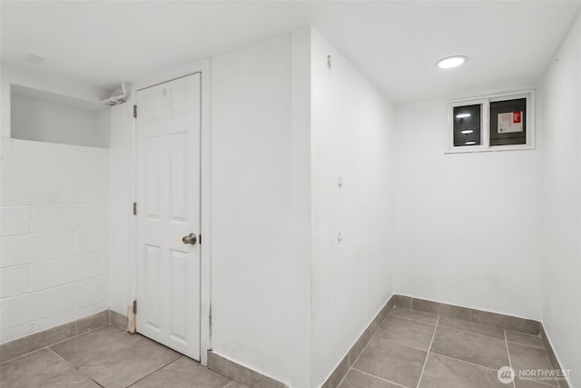 below grade area with tile patterned flooring and baseboards