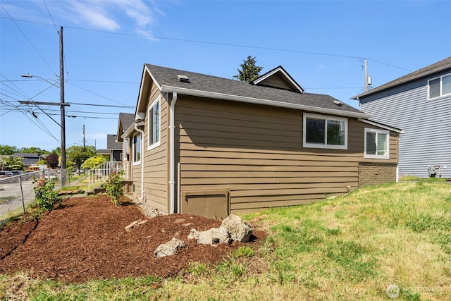 view of side of home with fence and a shingled roof