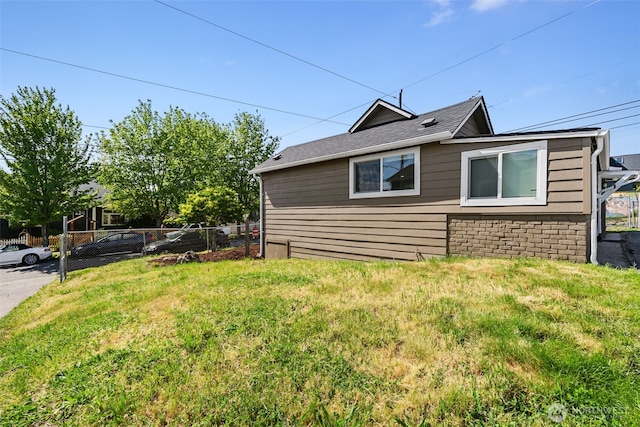 view of side of property with a lawn and fence