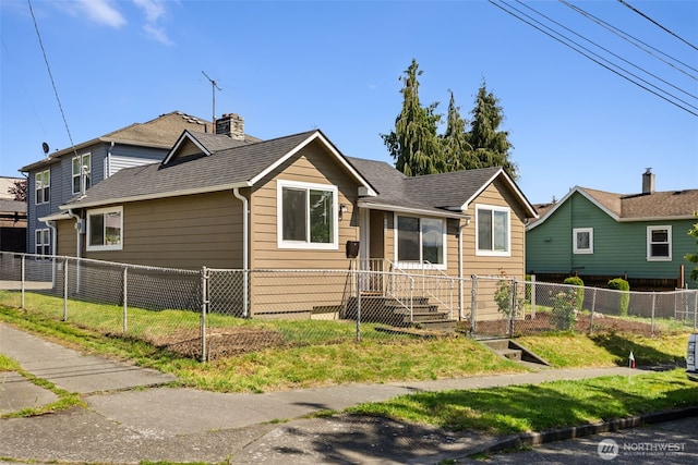 view of front facade featuring a fenced front yard, a chimney, a shingled roof, and a front yard