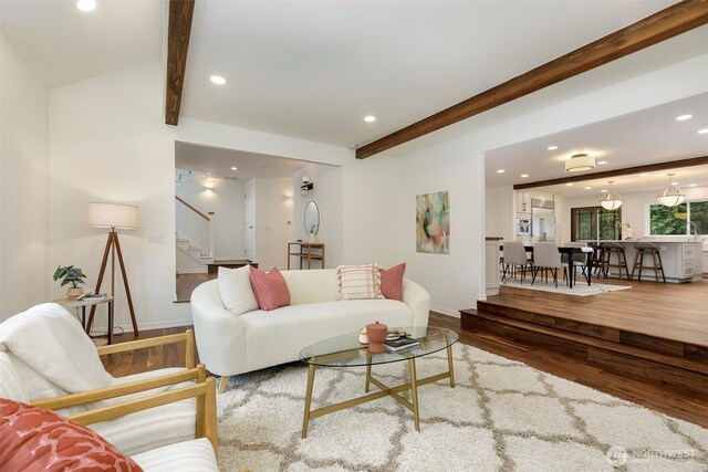 living area with beam ceiling, stairway, recessed lighting, and wood finished floors