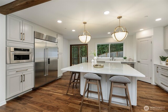 kitchen with dark wood finished floors, appliances with stainless steel finishes, light countertops, and a sink