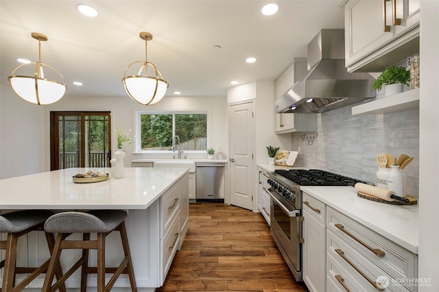 kitchen featuring wall chimney range hood, light countertops, recessed lighting, stainless steel appliances, and dark wood-style flooring