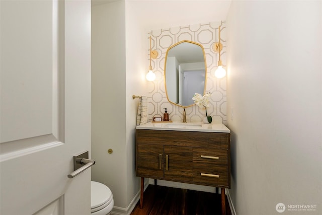 bathroom with vanity, wood finished floors, baseboards, toilet, and backsplash