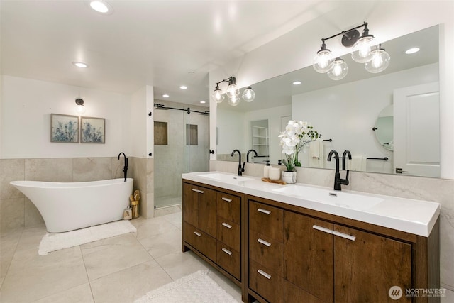 bathroom featuring a sink, tile walls, a stall shower, and double vanity