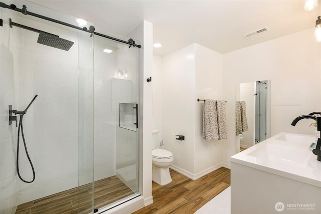 bathroom with visible vents, toilet, wood finished floors, and a shower stall