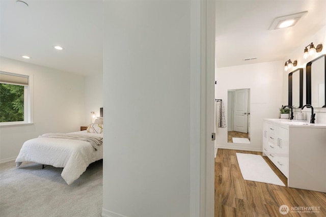 bedroom with visible vents, baseboards, recessed lighting, wood finished floors, and a sink