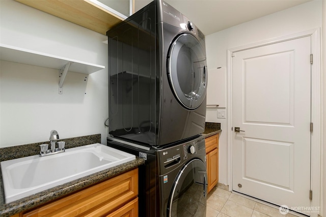 laundry room featuring a sink, cabinet space, light tile patterned flooring, and stacked washer / dryer