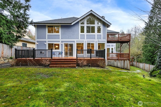 rear view of property featuring a wooden deck, a lawn, a chimney, and fence