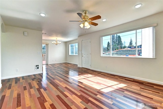 empty room with ceiling fan with notable chandelier, recessed lighting, wood finished floors, and baseboards