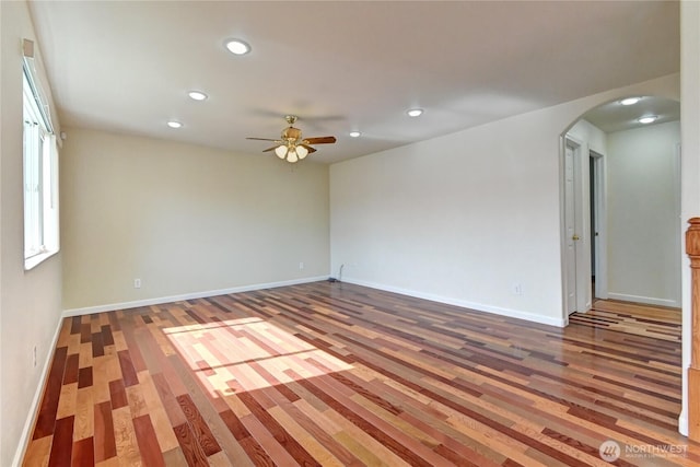 unfurnished room featuring recessed lighting, baseboards, arched walkways, and wood finished floors