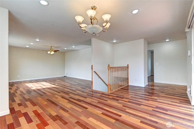 unfurnished room with recessed lighting, baseboards, wood finished floors, and ceiling fan with notable chandelier