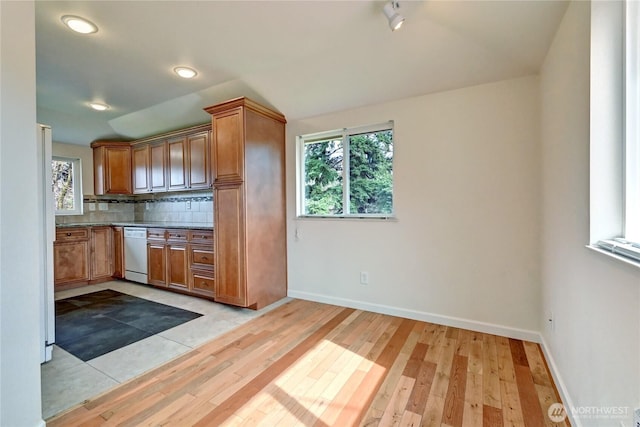 kitchen featuring dishwasher, plenty of natural light, light wood-style floors, and tasteful backsplash