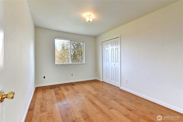 unfurnished bedroom featuring light wood finished floors, a closet, and baseboards