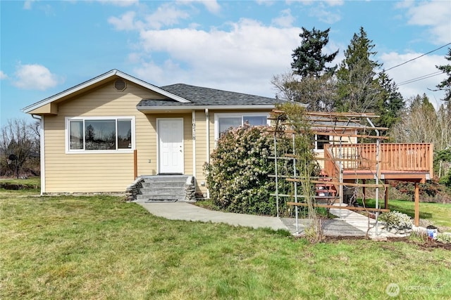 view of front of house with a deck, a front yard, and roof with shingles