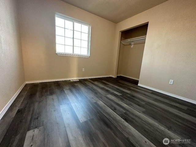 unfurnished bedroom with a closet, dark wood-type flooring, and baseboards